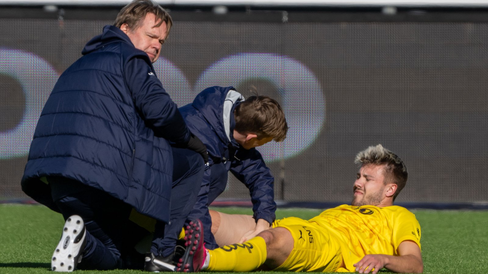 Fredrik André Bjørkan ligger nede med skade mot Strømsgodset. Han vrir seg i smerte mens det medisinske apparatet følger med. 