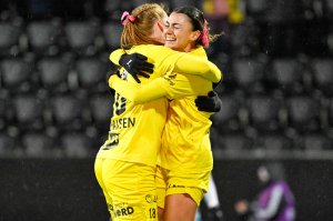 Claudia Cagnina og Anna Johansen klemmer hverandre og smiler i gule drakter med rosa sløyfe i håret under kampen mot viking på Aspmyra høsten 2024.