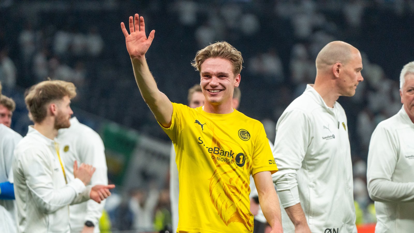 En smilende Jeppe Kjær i gul drakt vinker til publikum mot Tottenham. 
