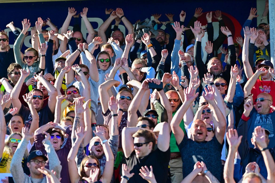 Publikum på Aspmyra tar bølgen for miljøet under kampen mot Strømsgodset. 