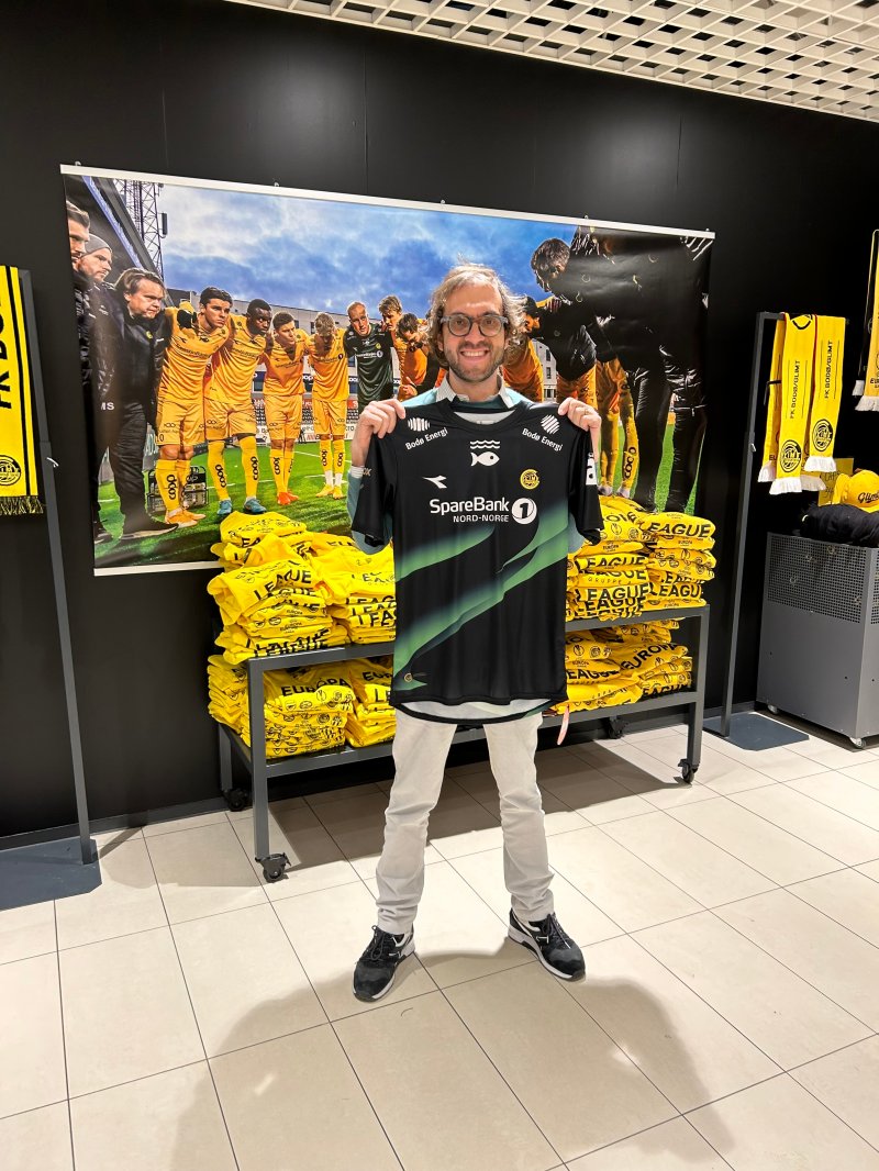 Eier og administrerende direktør Enrico Moretti Polegato holder stolt opp nordlysdrakten i Glimt-Shopen. Foto: Privat